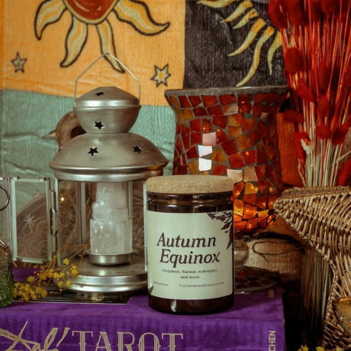 Decorative setup with tarot cards, candle labeled 'Autumn Equinox', and lantern on a purple cloth.