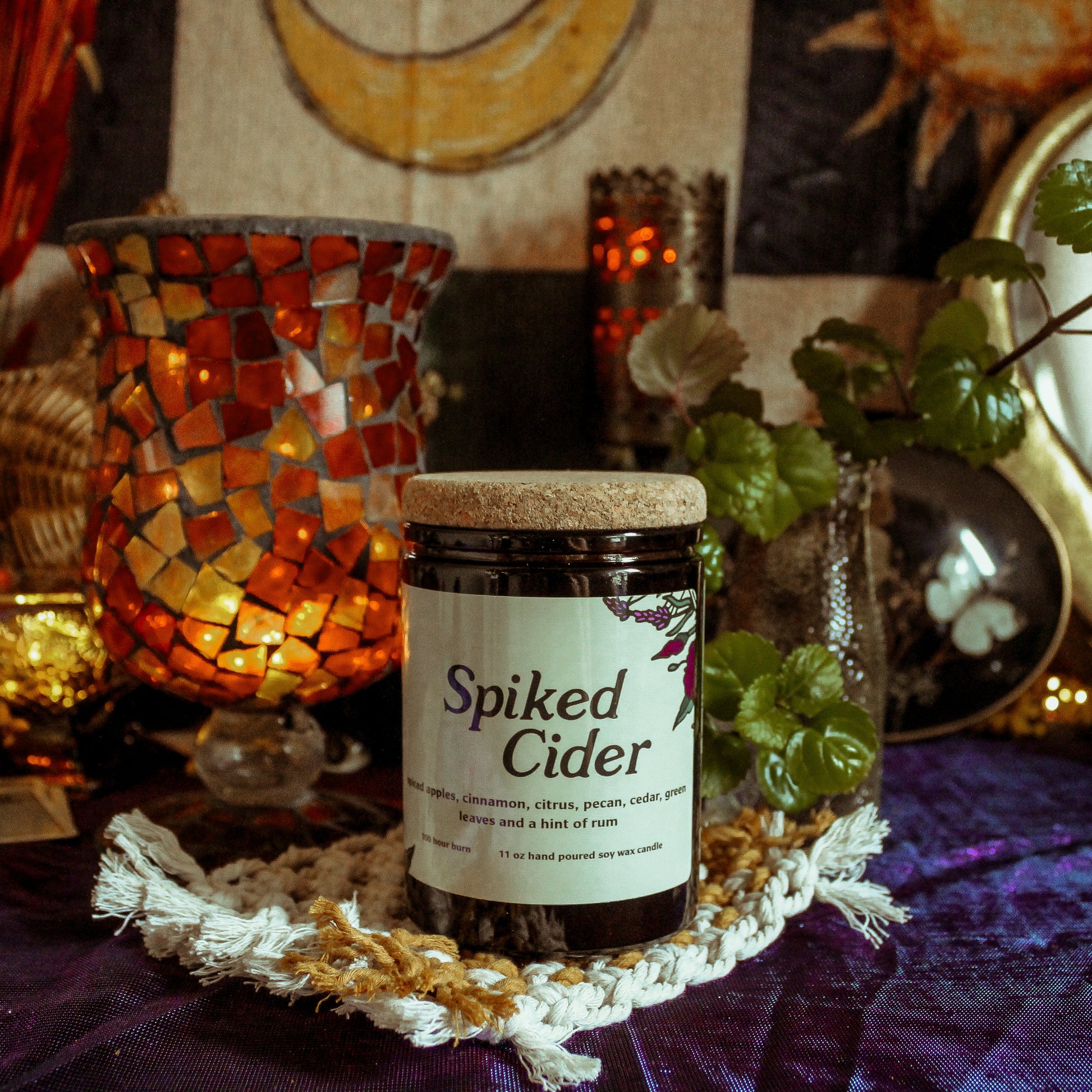 Jar of 'Spiked Cider' on a decorative table with candles and plants