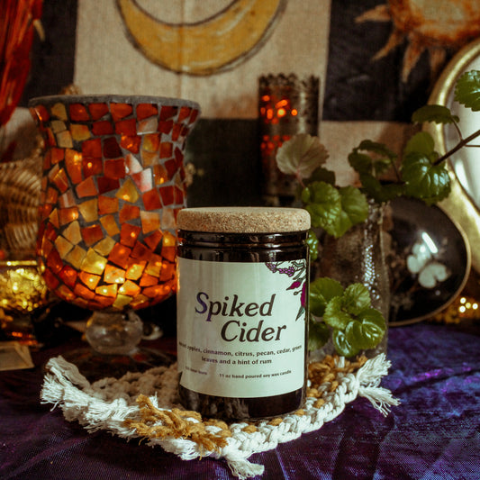Jar of 'Spiked Cider' on a decorative table with candles and plants