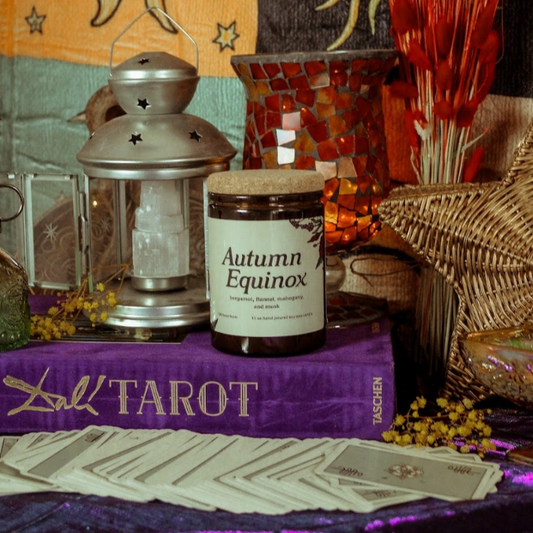 Autumn Equinox candle on a table with tarot books and decorative items.