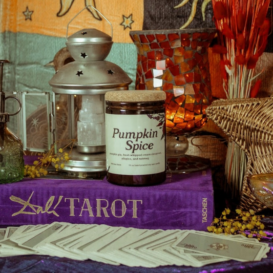 Pumpkin spice candle on a tarot card with tarot cards and lantern in the background