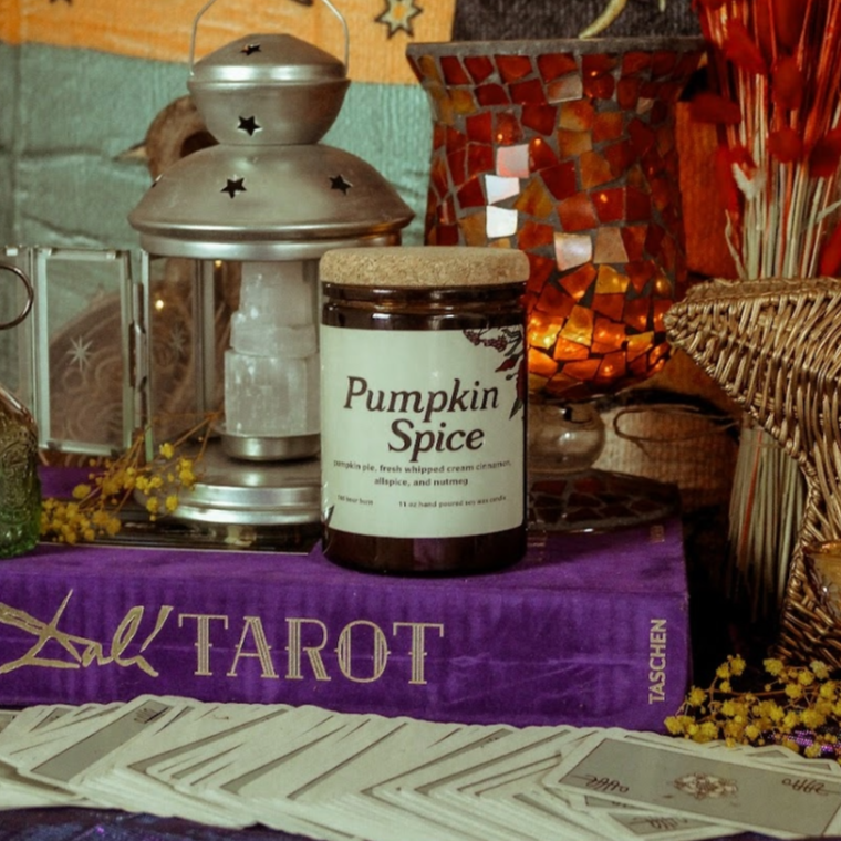 Pumpkin spice jar on a tarot table with candles and cards