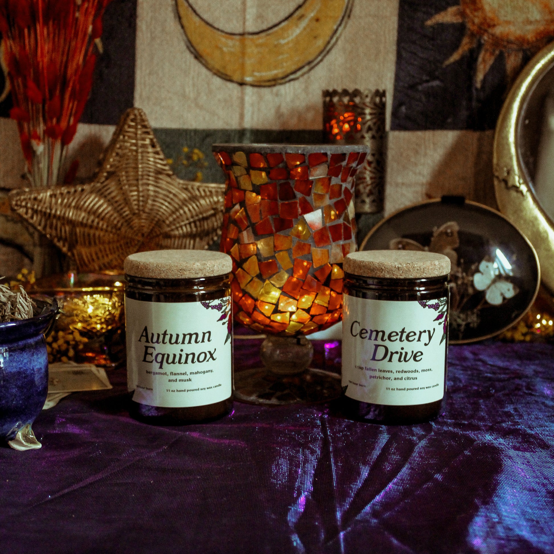 Two jars labeled 'Autumn Equinox' and 'Cemetery Drive' on a table with mystical decor.