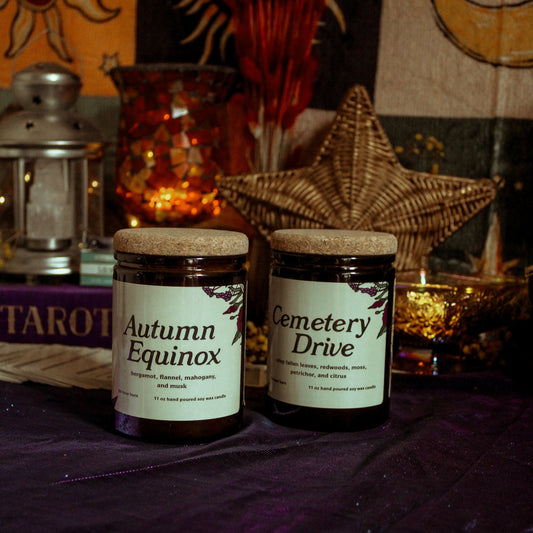 Two jars labeled 'Autumn Equinox' and 'Cemetery Drive' on a table with mystical decor.