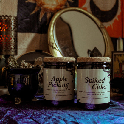Two jars labeled 'Apple Picking' and 'Spiked Cider' on a table with a mystical background.