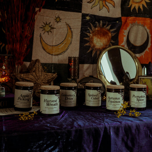 fall candles on a table with celestial-themed decor in the background.