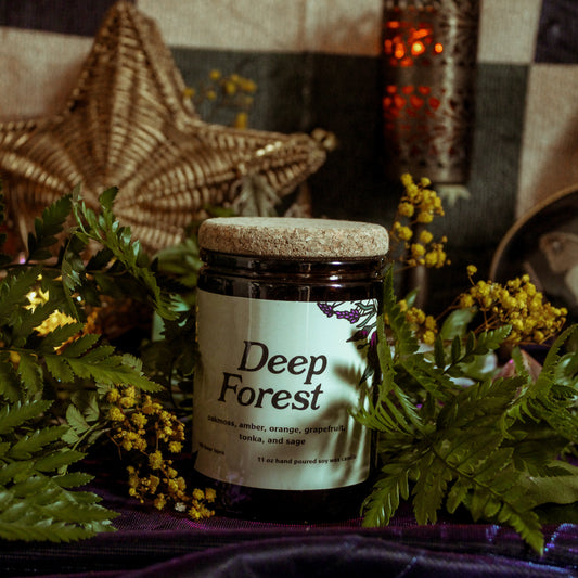 Jar labeled 'Deep Forest' surrounded by greenery on a textured surface with a star and moon decoration in the background.