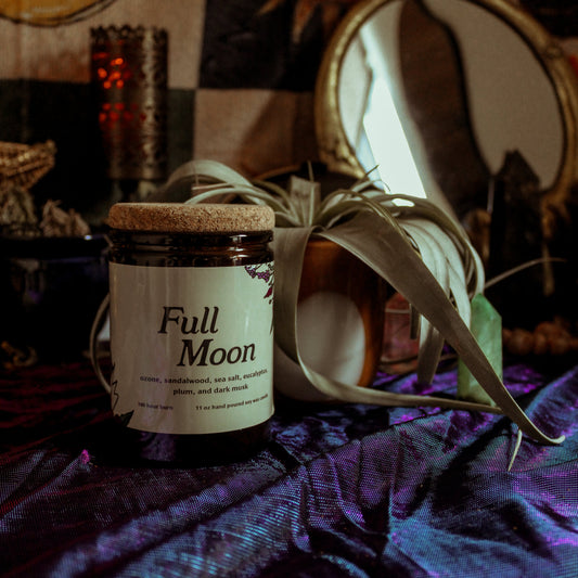 Candle labeled 'Full Moon' on a textured surface with a mystical background