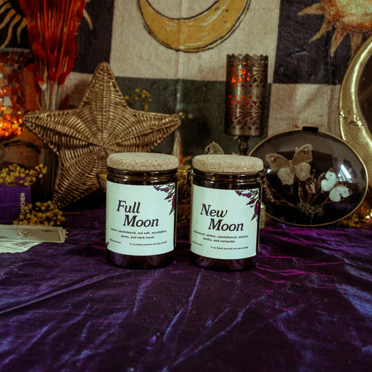 Two candles labeled 'Full Moon' and 'New Moon' on a purple surface with celestial decorations.